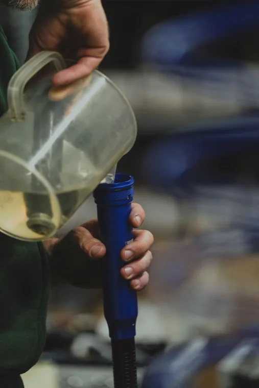 Lainer technician filling a shock absorber with oil